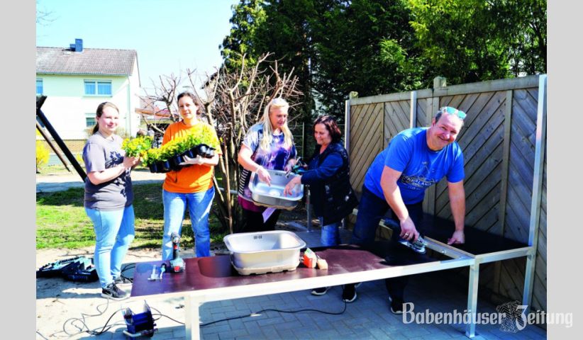 Hauptprojekt der Renovierungsaktion im Kindergarten war die Matschk&uuml;che, in der in Zukunft leckerer Sandkuchen und Kr&auml;utersuppe zubereitet wird. (Von rechts nach links) Frank Volk zeigt sich f&uuml;r Untergestell und Arbeitsplatte verantwortlich, w&auml;hrend die Leiterin Eva-Maria Hartmann und Tatjana Meyer-Hitzel vom Elternbeirat die Sp&uuml;lenfunktion testen. Weitere Helferinnen begutachten die gespendeten Blumen und beratschlagen, wo diese im Garten am besten zur Geltung kommen.